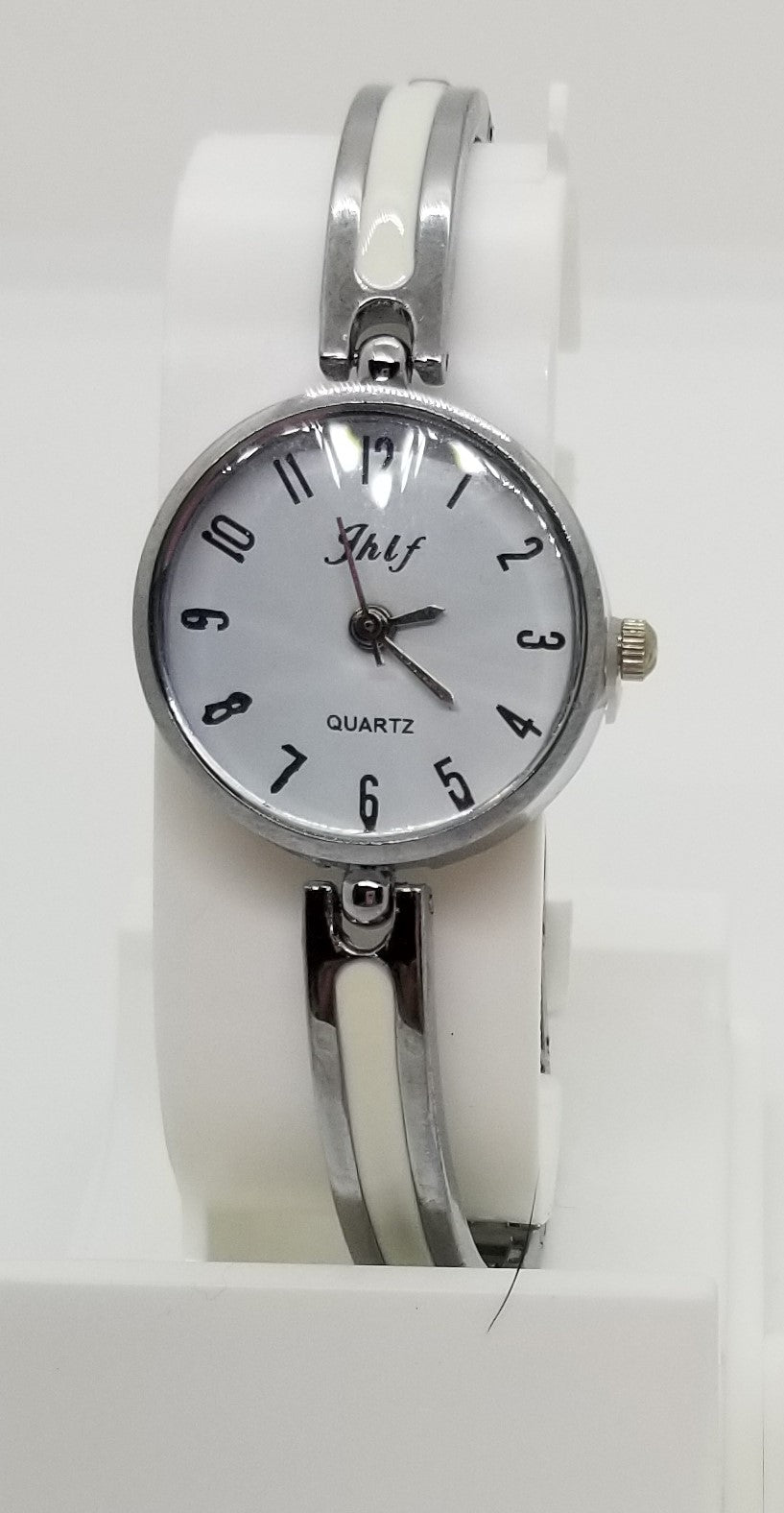 Silver base metal watch with large numbers and a white strip in strap